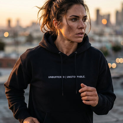 Woman wearing a black hoodie with text, standing on a rooftop with a cityscape background.